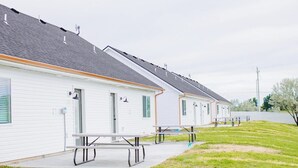 Une rangée de maisons mobiles de plain-pied, chacune dotée d’une véranda et de tables de pique-nique.