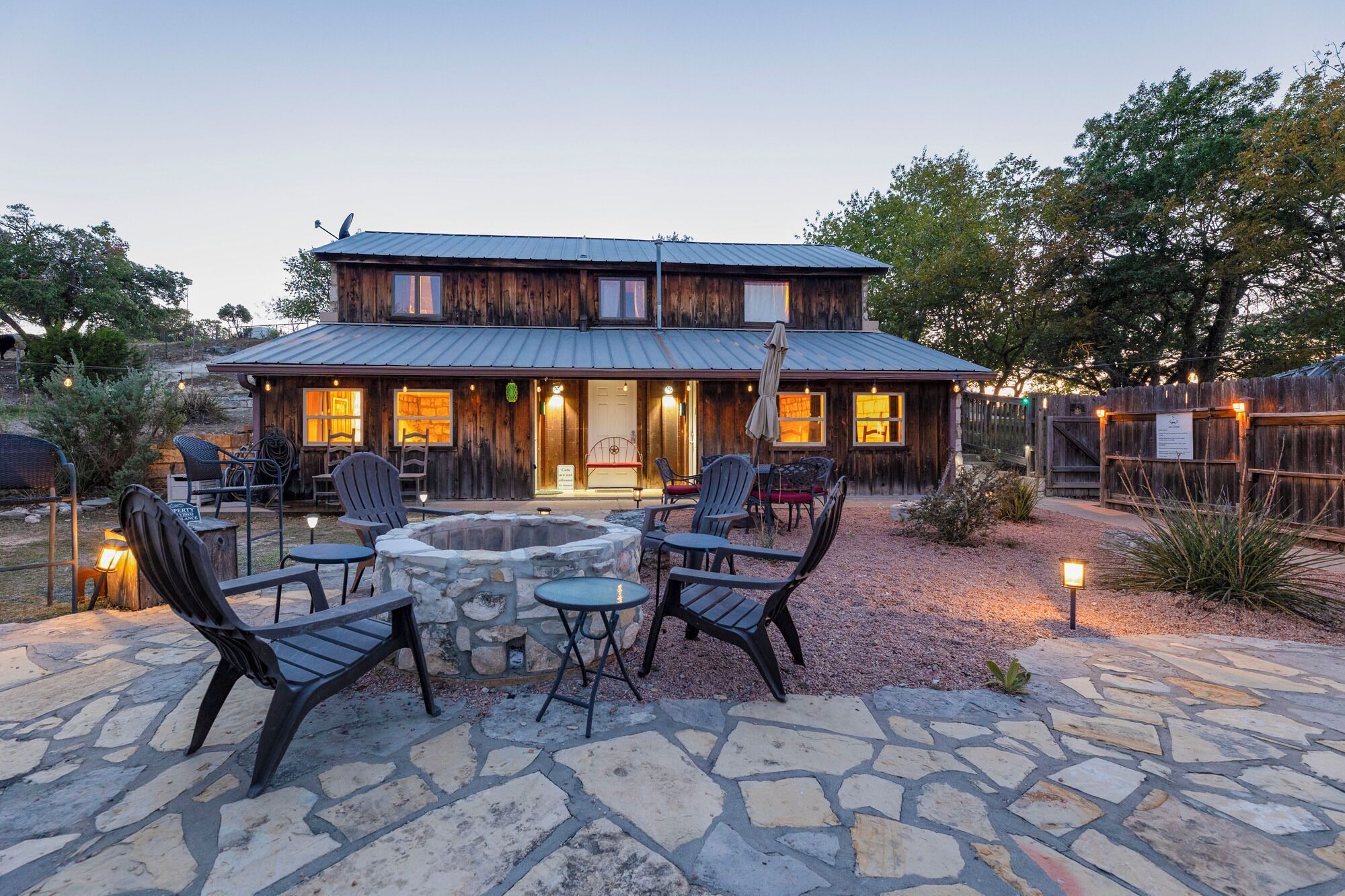 A rustic wooden building with a stone patio, outdoor seating, and a fire pit.