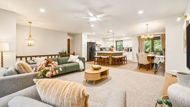 A spacious living room with a sofa, a coffee table, and a dining area with chairs and a table. - The Poolside farm house (Omaha)