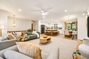A spacious living room with a sofa, a coffee table, and a dining area with chairs and a table.