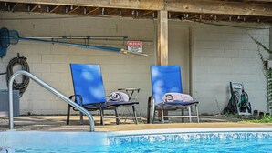 A swimming pool with two blue lounge chairs and a warning sign on the wall. - The Poolside farm house (Omaha)