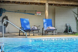Ein Schwimmbecken mit zwei blauen Liegestühlen und einem Warnschild an der Wand.