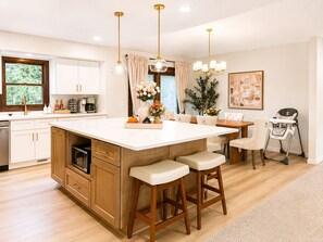 Une cuisine moderne dotée d’un îlot central, de meubles en bois et de luminaires suspendus.