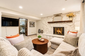 A modern living room with a fireplace, comfortable seating, and a television.