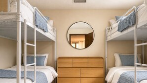 A room with bunk beds, a wooden headboard, and a round mirror on the wall. - The Poolside farm house (Omaha)