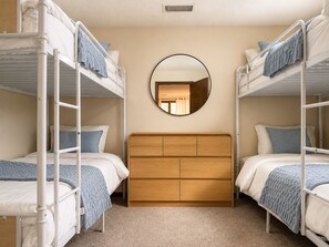 Ein Zimmer mit Etagenbetten, einem Holz-Kopfteil und einem runden Spiegel an der Wand.