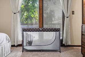 A room with a bed, a window with blinds, and a table with a patterned tablecloth.