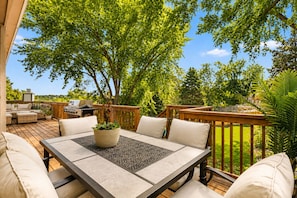 An outdoor patio with a table, chairs, and a grill.