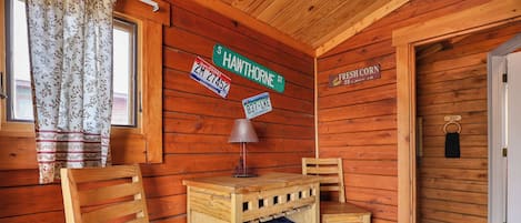 A wooden cabin interior with a desk, two chairs, a lamp, and a sign indicating Shawthorne St.