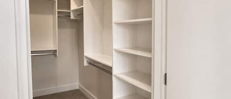 A walk-in closet with open shelves and a carpeted floor.