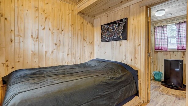 Ein Zimmer mit Holzwänden, einem Bett, einer Karte an der Wand und einer Tür, die in einen anderen Raum führt.