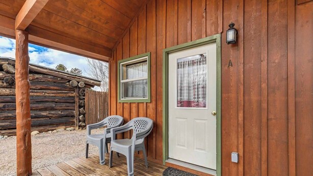 A wooden cabin with a porch, two plastic chairs, a door with a window, and a mailbox. - Our Cabin is great for youth groups, reunions and families! (Buena Vista)