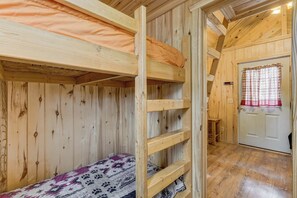 A wooden interior with a bunk bed, a door, and a window with curtains. - Our Cabin is great for youth groups, reunions and families! (Buena Vista)