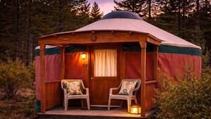 Eine Holzjurte mit zwei Stühlen und einer Laterne auf der Veranda.