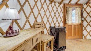 Una tenda con interni in legno, un tavolo con una lampada, una sedia e un elettrodomestico nero.