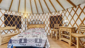 L'interno accogliente di una yurta, con un letto, mobili in legno e una parete a griglia.