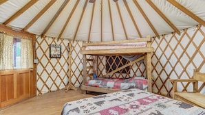 Una yurta con un letto a castello, una sedia di legno e un quadro appeso al muro.