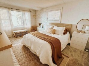 Ein Schlafzimmer mit einem großen Bett, einem Nachttisch, einem Sessel und einer Heizung.
