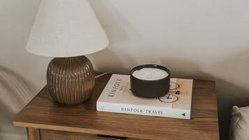 Une table de chevet avec une lampe, une bougie et un livre intitulé « KINFOLK TRAVEL ».