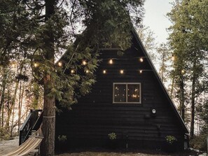 A cabin with a triangular roof, a window, and a staircase leading up to a deck.