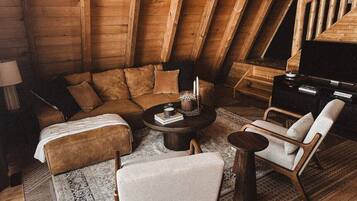 Een knus loft-appartement met houten plafond, een zithoek, een salontafel en een stoel.