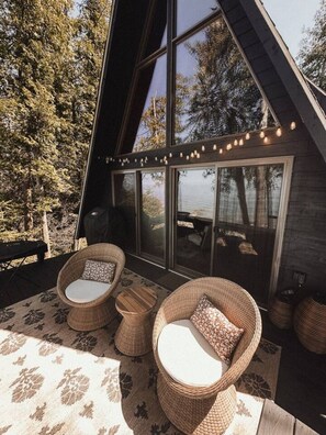 Un espacio exterior acogedor con mobiliario de mimbre y vistas al bosque.