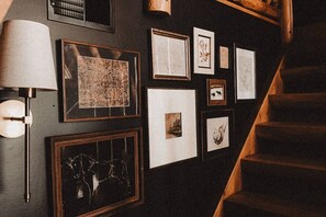A staircase with a wall adorned with framed pictures and a wall-mounted lamp.