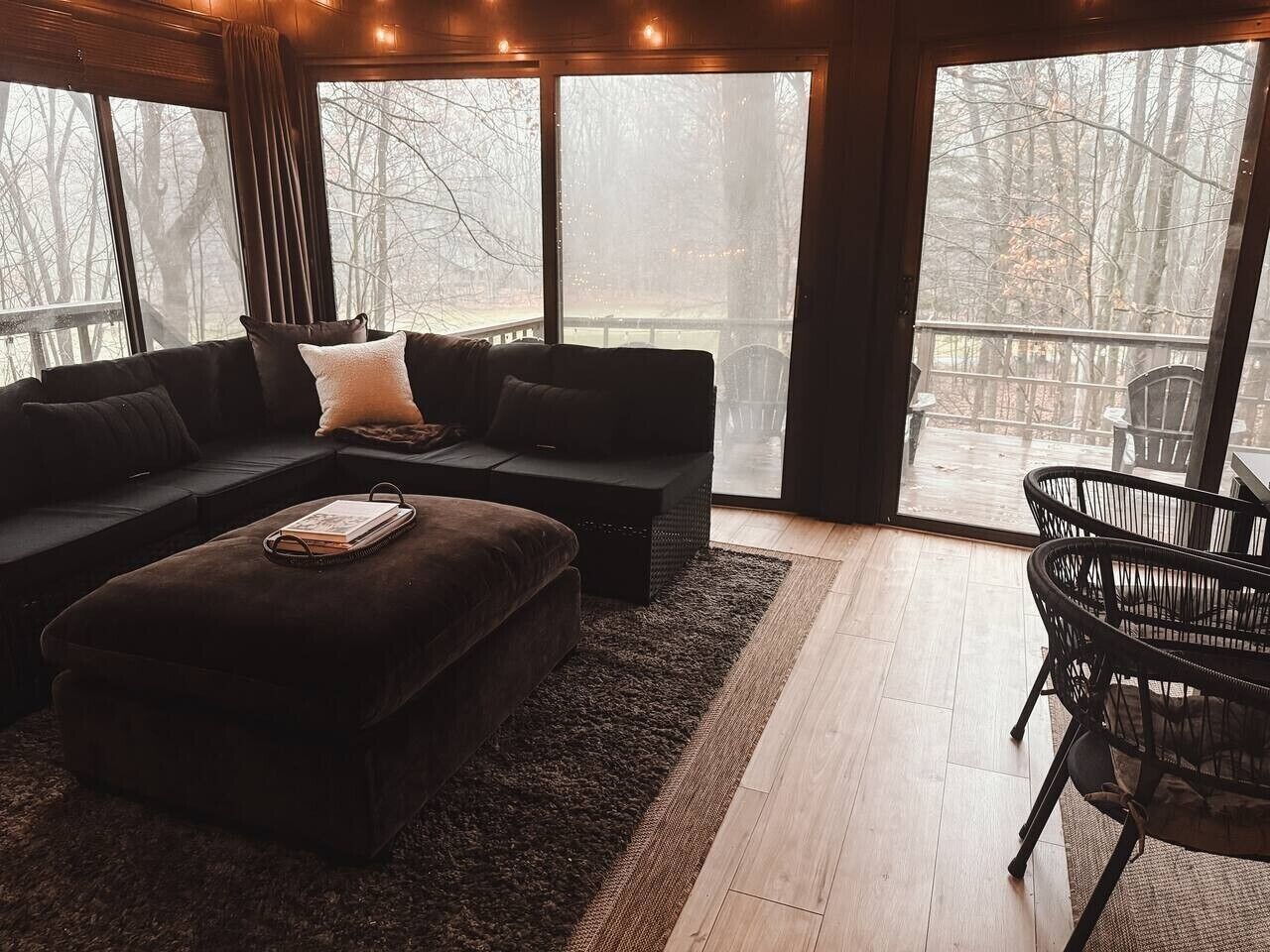 A cozy living room with a sectional sofa, ottoman, and a small table with chairs.