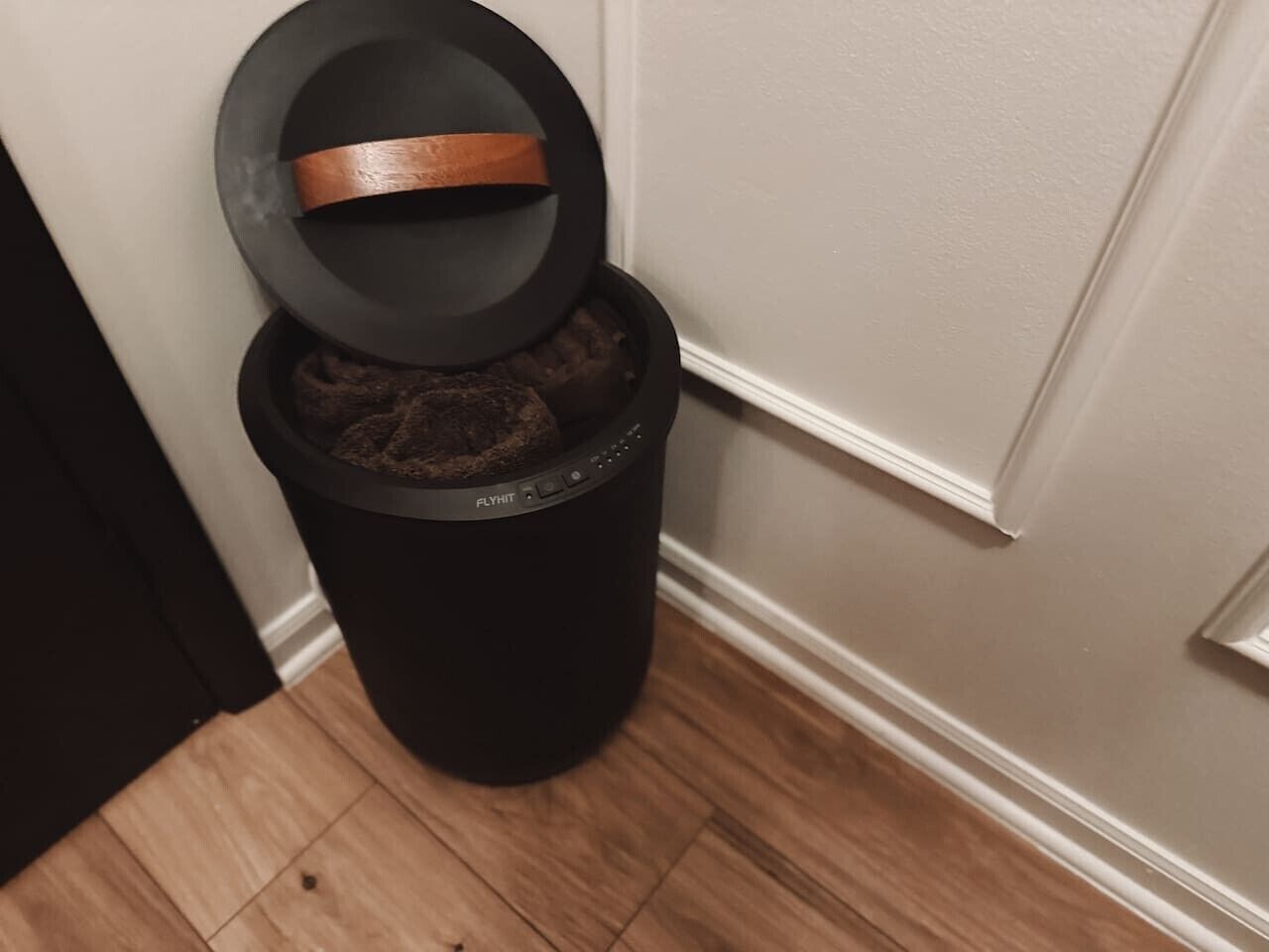 A trash can with a lid and a black trash bag inside.