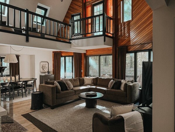 A spacious living room with a large sectional sofa, a coffee table, and a dining area with a table and chairs.