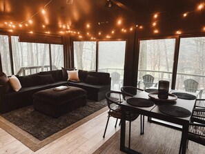 A cozy living room with a sofa, ottoman, and dining table set with chairs.