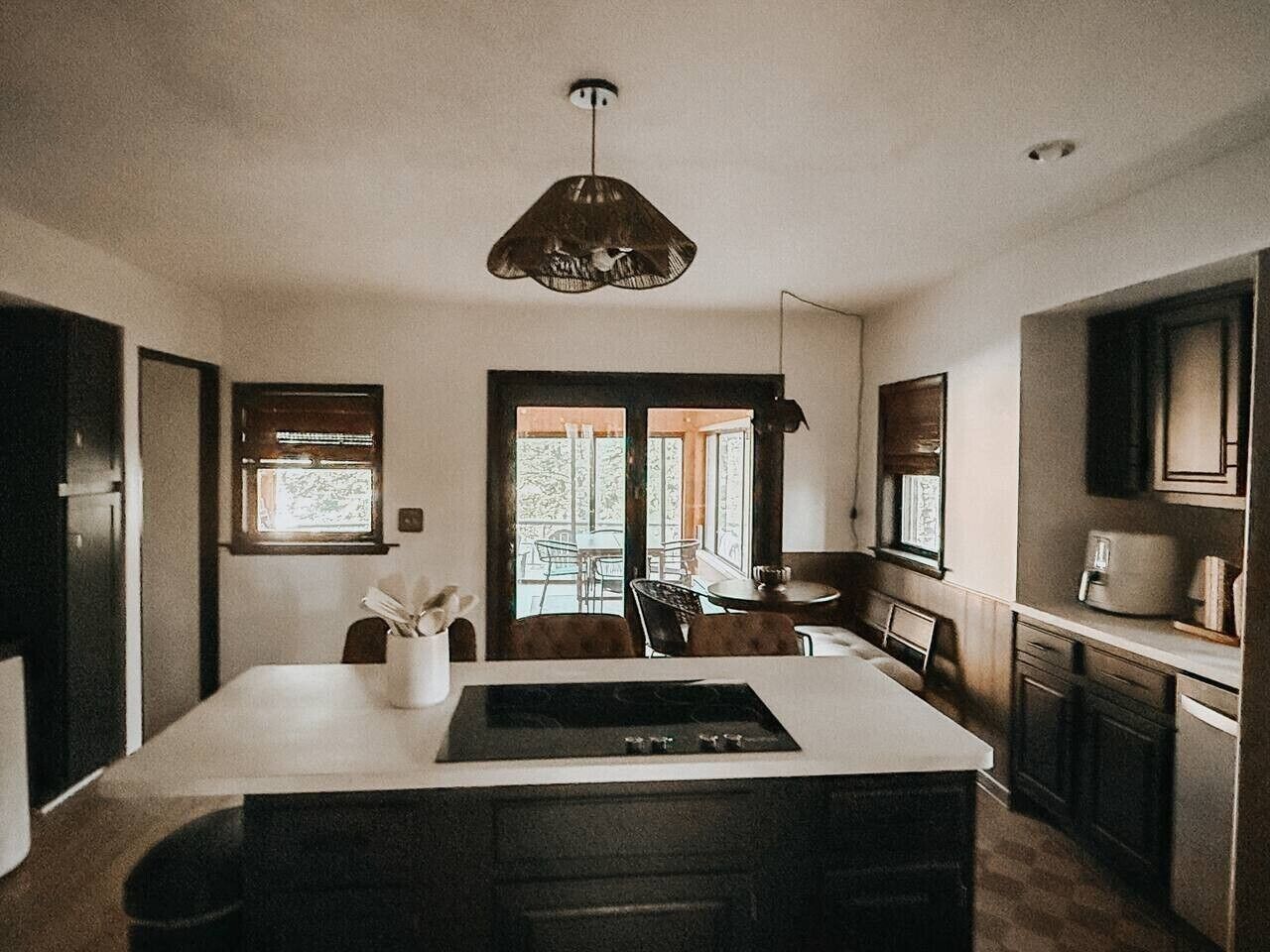 Een moderne keuken met een centraal eiland, inbouwapparatuur en een groot raam dat voor natuurlijk licht zorgt.