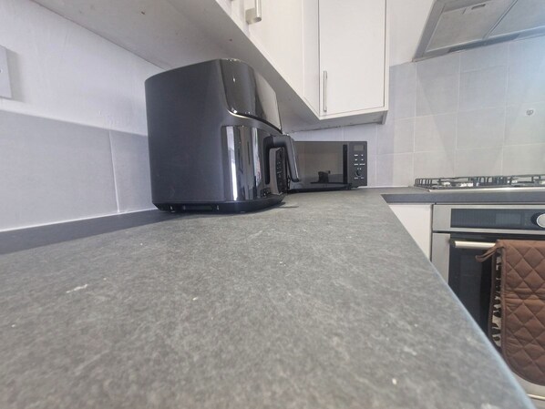 A kitchen with a stainless steel refrigerator, a microwave, and a stove.