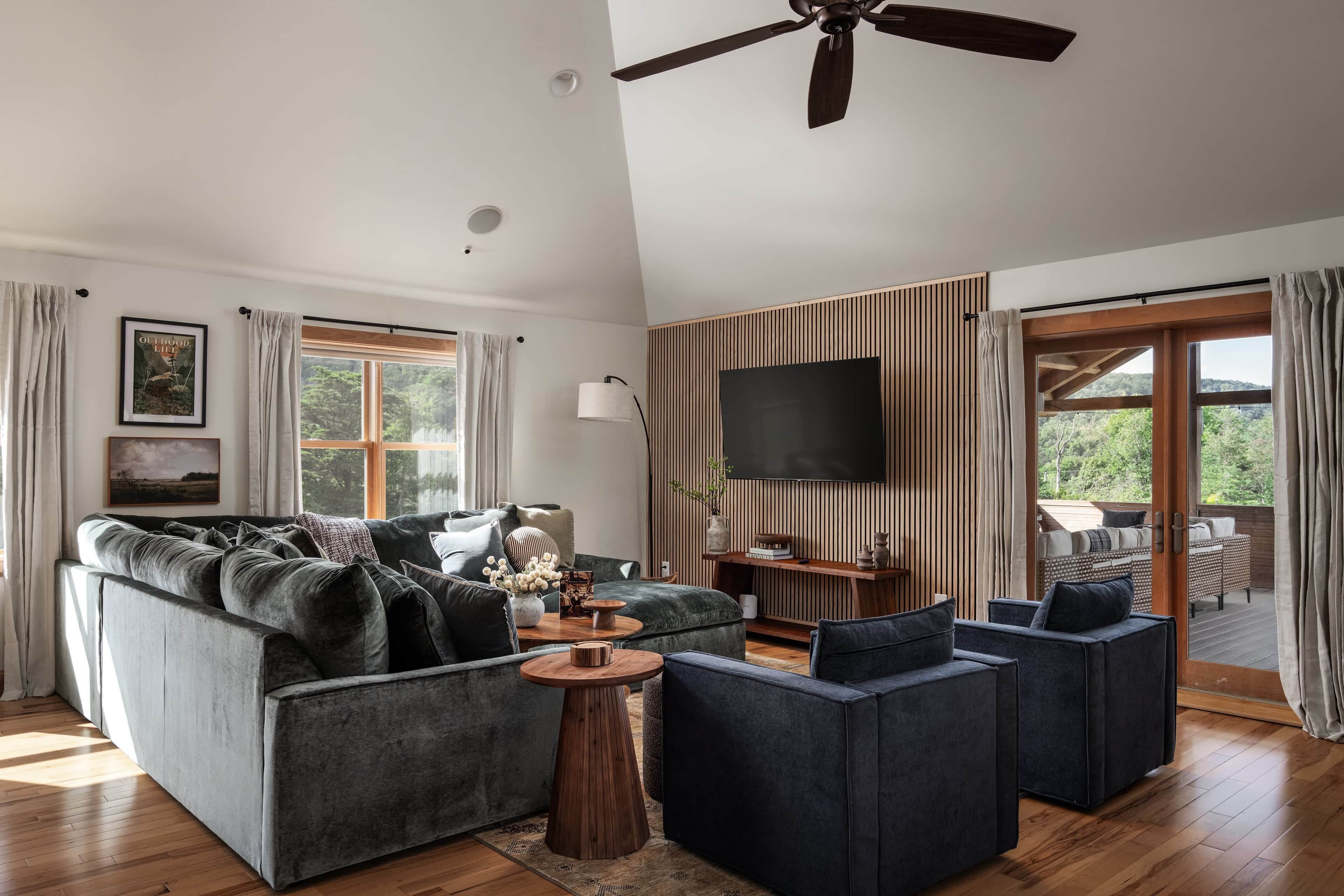 A modern living room with a sofa, armchairs, a coffee table, and a TV.