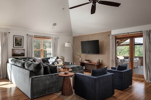 A modern living room with a sofa, armchairs, a coffee table, and a TV. - Stylish & Modern Cabin: Hot Tub, Sauna, Pickleball (Berkeley Springs)