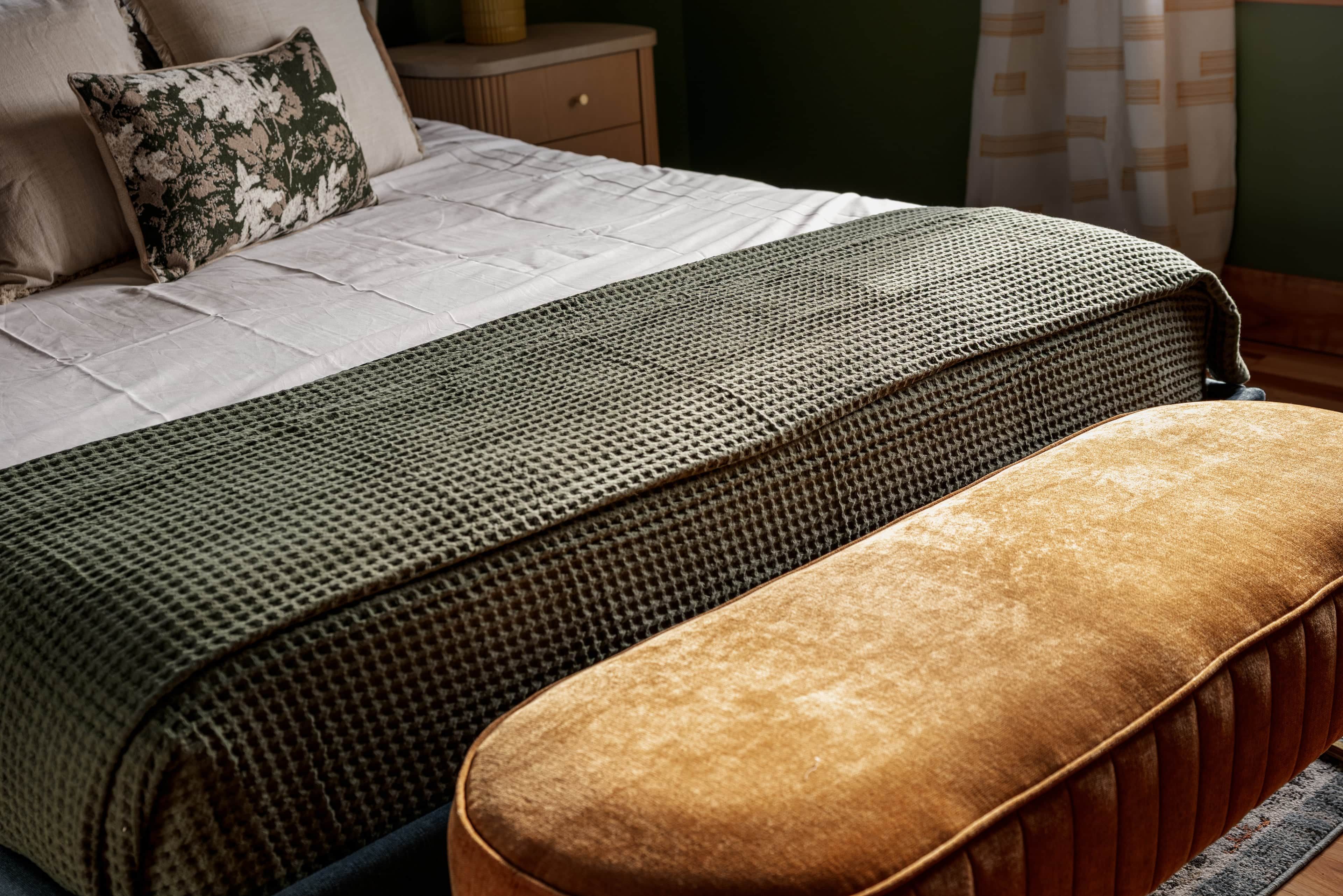 A neatly made bed with a patterned bedspread and a matching bench.