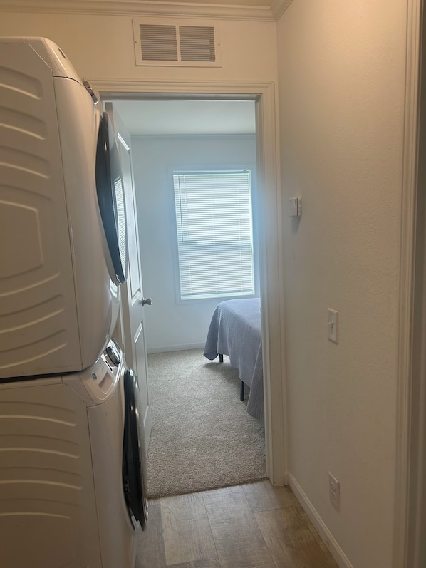 Un pasillo estrecho que conduce a un dormitorio con cama y ventana.