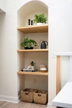 A corner shelving unit with plants, books, and kitchenware. - C-Street Art Loft (Springfield)