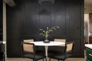 A dining area with a round table, four chairs, and a vase with flowers. - C-Street Art Loft (Springfield)