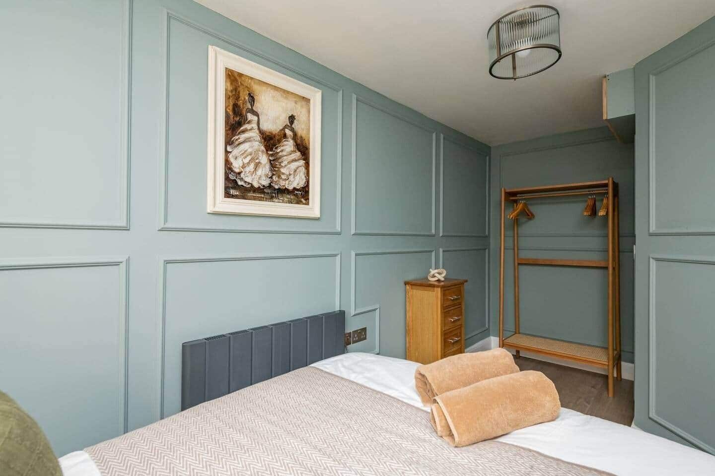 Ein Schlafzimmer mit einem Bett, einem Schminktisch, einem Kleiderschrank und einem Bild an der Wand.