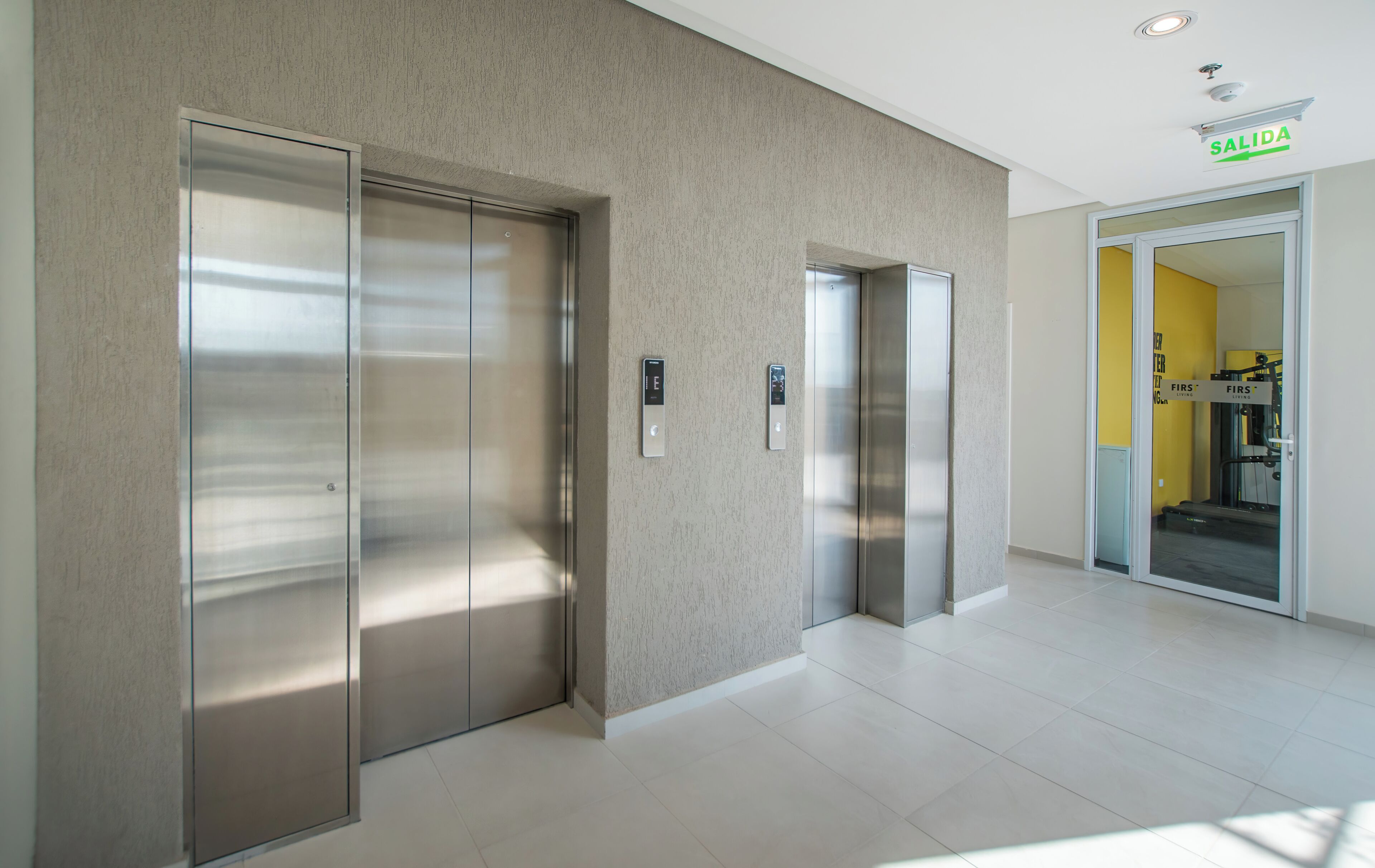 Un área de ascensor moderna con puertas metálicas y un panel de control en la pared.