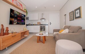 A modern living room with a sofa, a coffee table, and a TV mounted on the wall. - Corporate Stays First Living - 906 (Asunción)