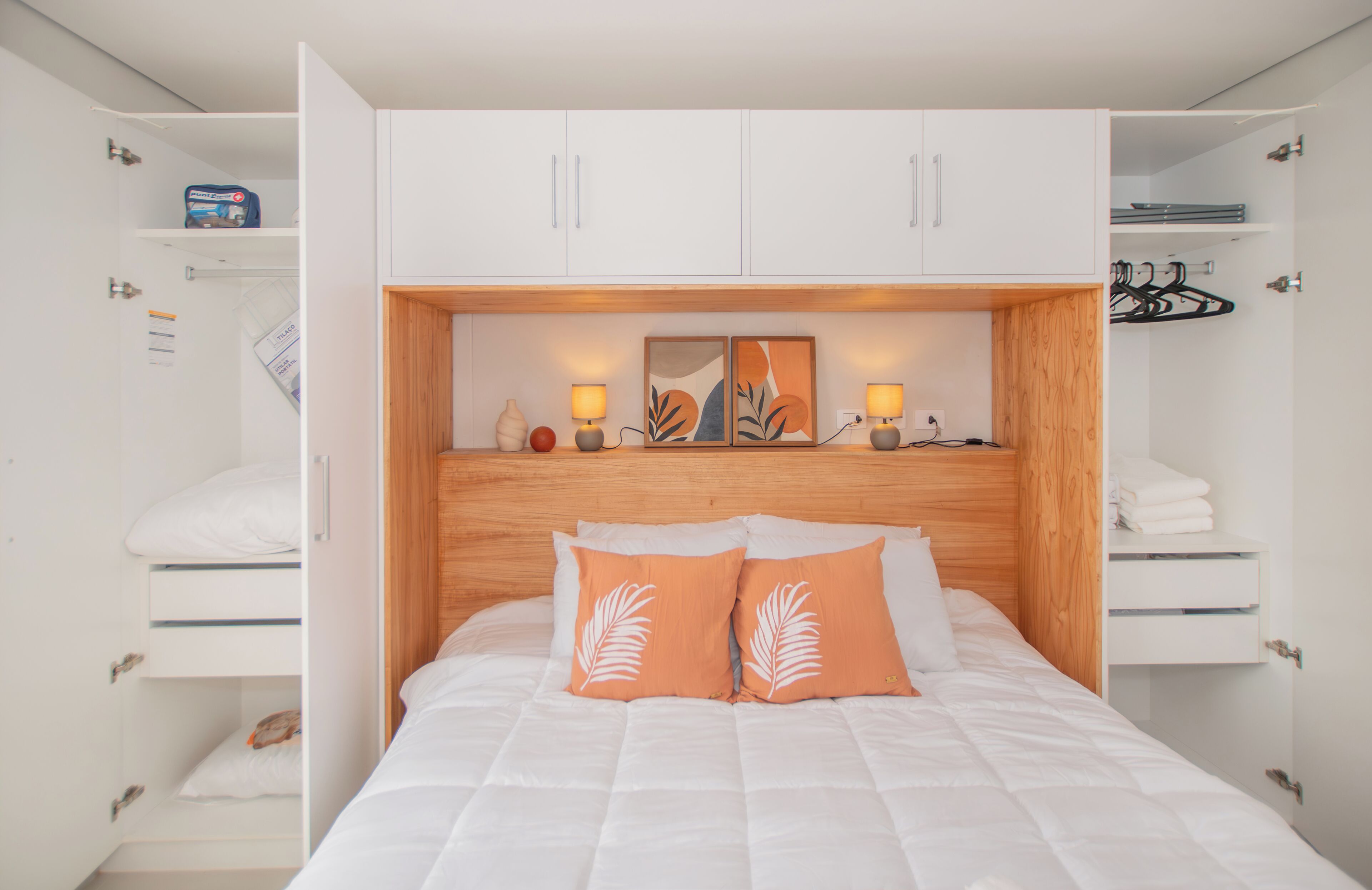 Um quarto com uma cama, duas mesas de cabeceira, um guarda-roupa e uma estante com objetos decorativos.
