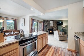 A modern kitchen with a built-in stove, wooden cabinets, and a large island with a kettle. - It's Four O'Clock Somewhere (Breckenridge)