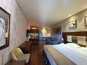 Ein Hotelzimmer mit Bett, einer Couch, einem Esstisch und einer Küchenzeile.