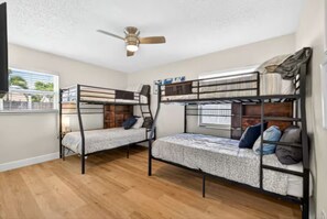 Ein Zimmer mit Etagenbetten, einem Deckenventilator und einem Fenster mit Jalousien.