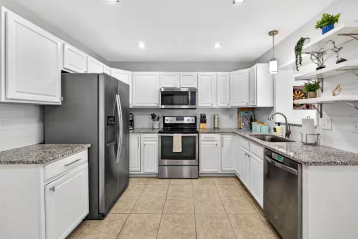 A modern kitchen with white cabinetry, stainless steel appliances, and a tiled floor.