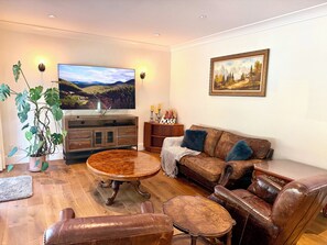 A living room with a television, a painting, a potted plant, and leather furniture. - Redwood 1-Acre Estate (Surrey)