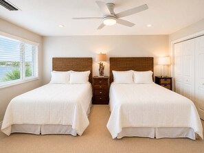 A hotel room with two beds, a ceiling fan, a nightstand with a lamp, and a view of the outdoors. - Needle Rush Point E34, Beach Access, 2 Pools, Riverfront, Private Beach (Pensacola)