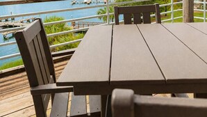 Um deck de madeira com mesa e cadeiras, com vista para uma marina e para a água.